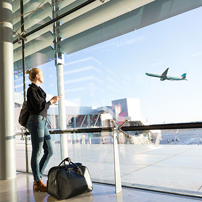 a woman waiting at an airport with travel bag