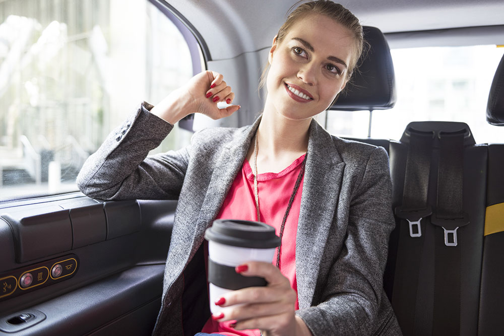Business woman with a coffee in a taxi
